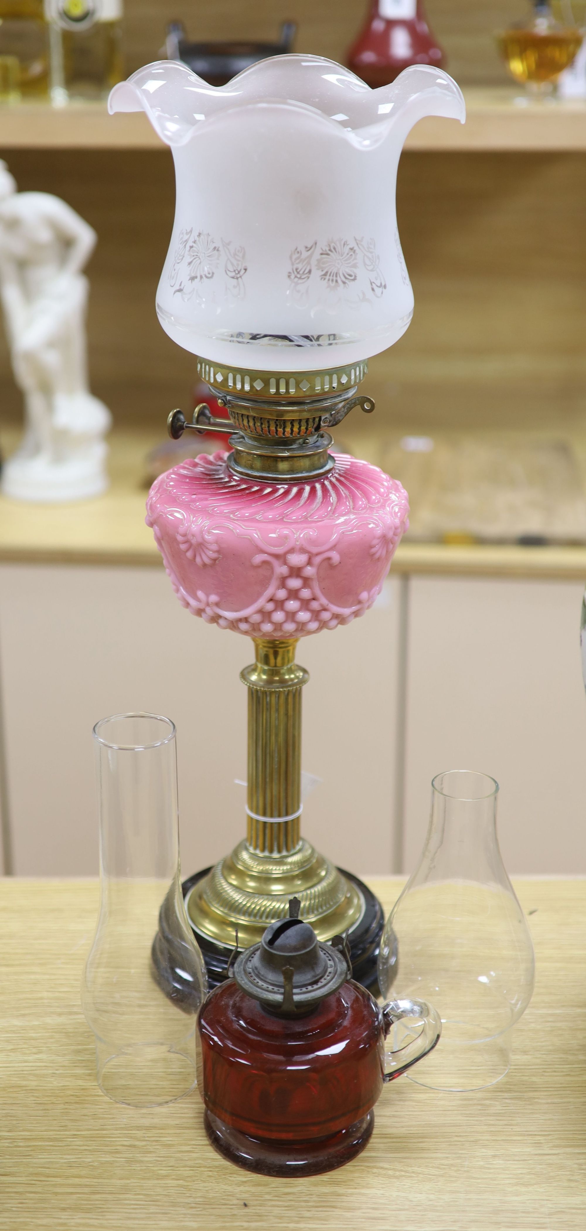 A late Victorian brass oil lamp with pink glass reservoir and a cranberry oil lamp